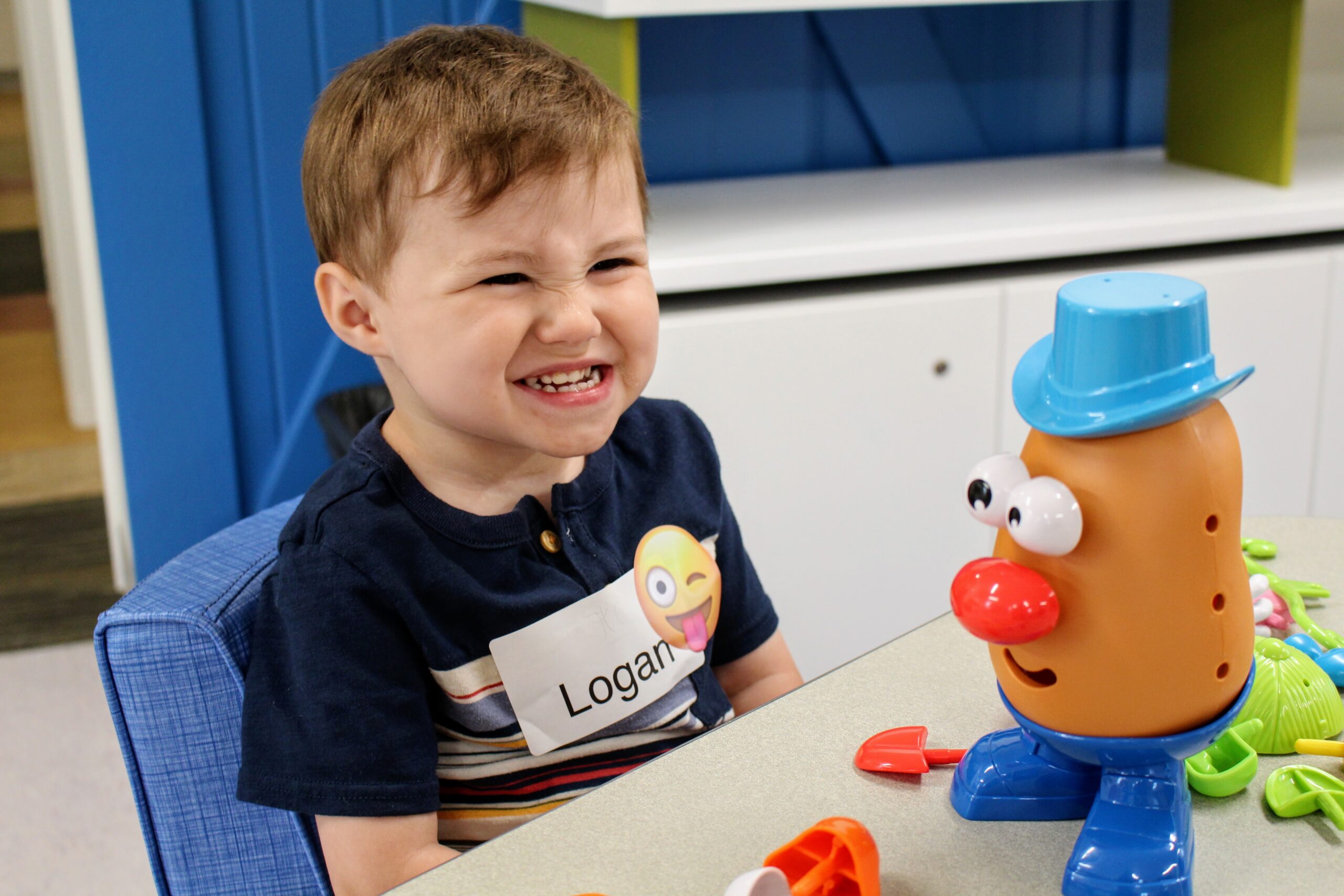 smiling boy playing with mr. potato head